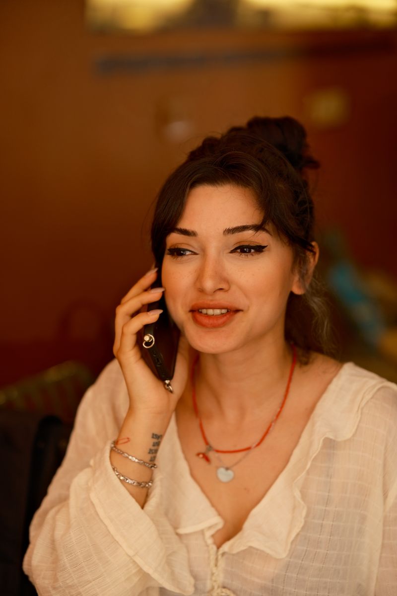 A smiling woman talking on the phone in a warm room