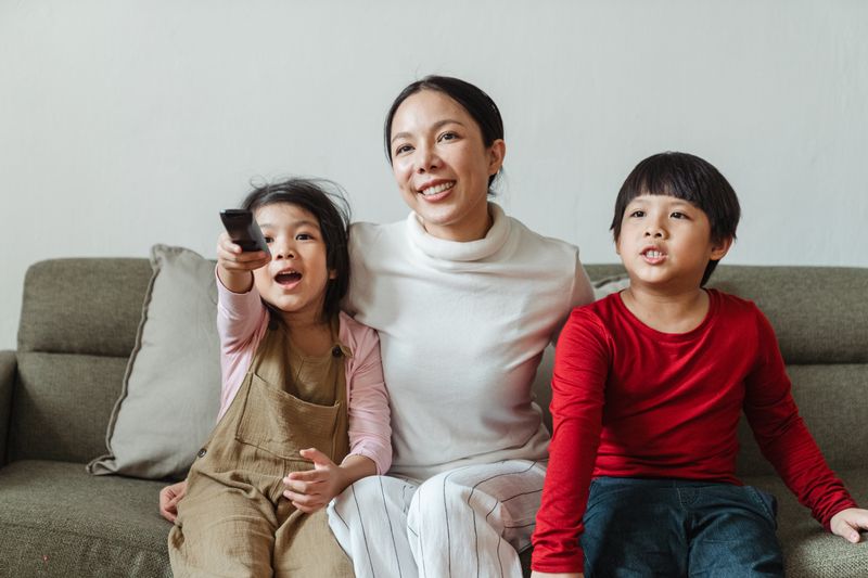A mother and two children watching together on the couch