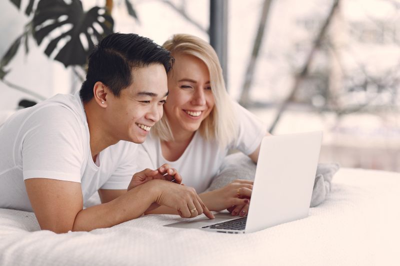 A young couple smiling at a laptop together